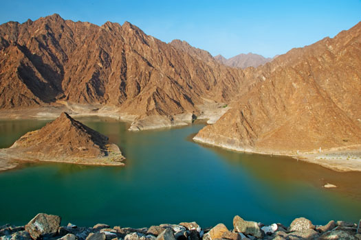 Blue water reservoir surrounded by rocky mountains