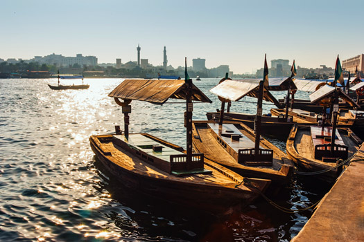 Old wooden boats on the creek of Dubai with old Dubai in the background