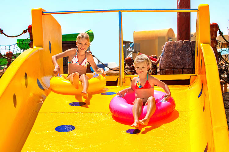 2 girls are having fun on a yellow water slide