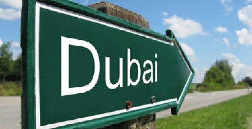 Green road sign pointing towards Dubai